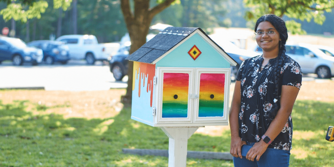A girl promoting peace through art therapy standing next to a colorful house in a park.