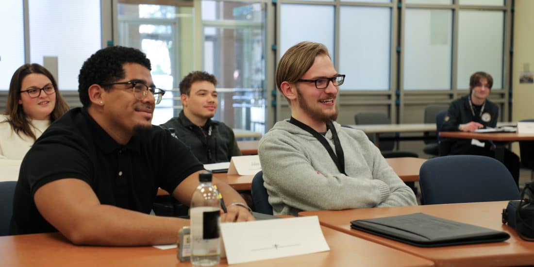 Students smile while sitting in classroom during lecture