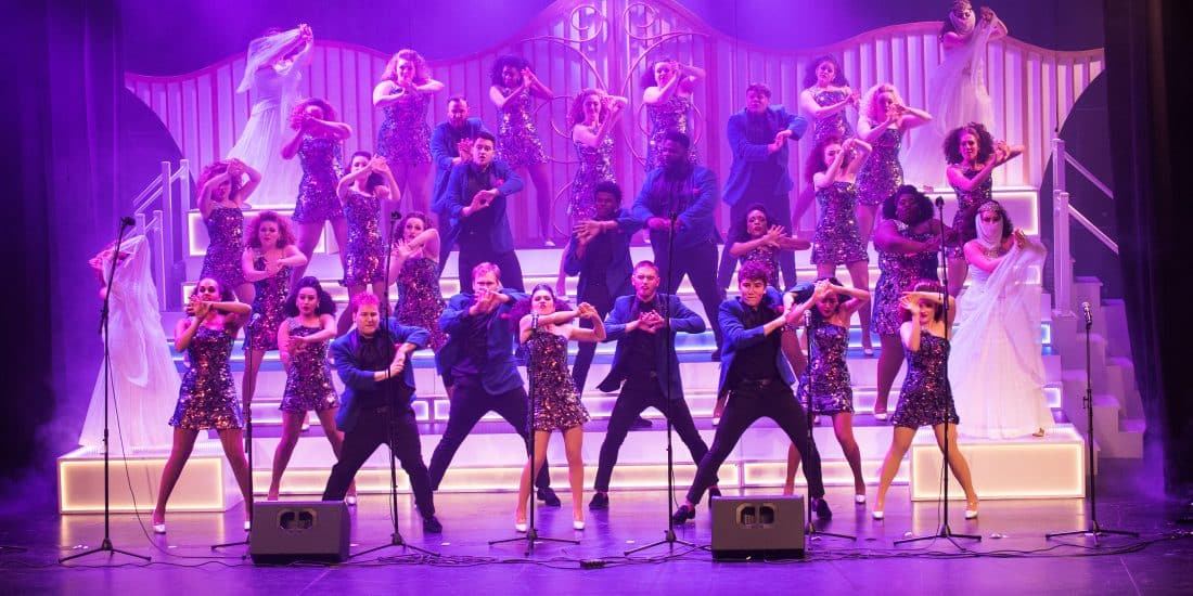 Wide shot Show choir performing on stage with dramatic lighting