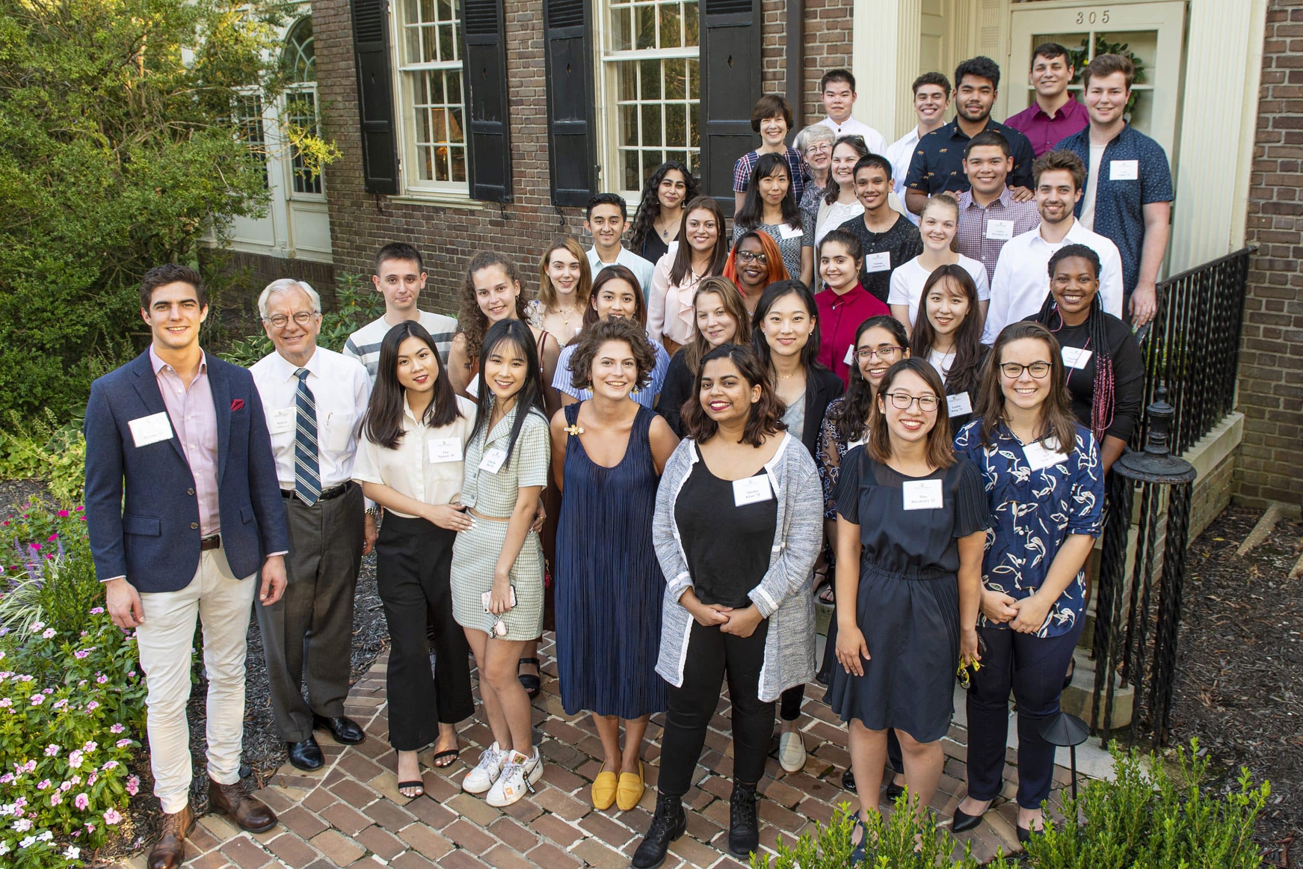 Group of multicultural students on the porch of the President's home with President Lindgren