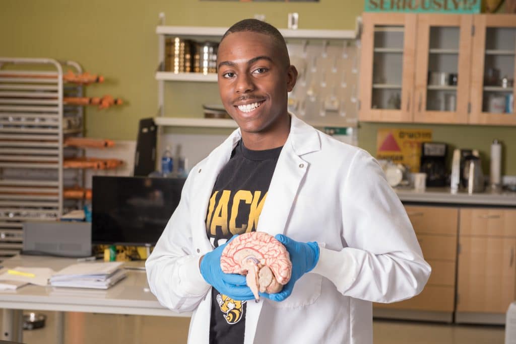 Behavioral neuroscience student smiles while holding a model cross section of a human brain