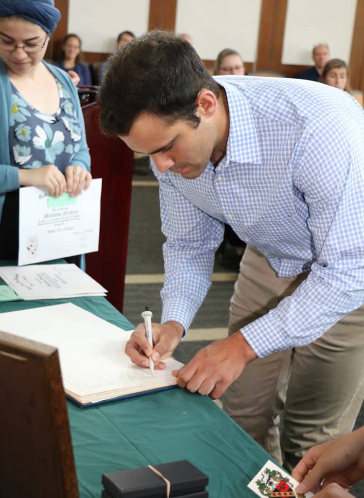 A man signing a paper at the Tri beta Honor society Induction