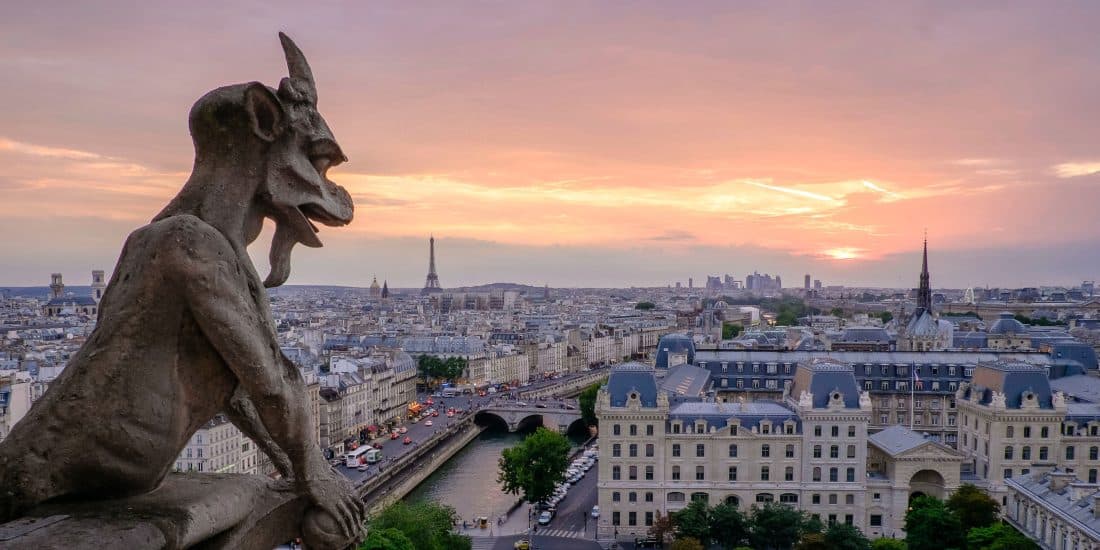 A stone gargoyle overlooks the Paris skyline looking at the city.