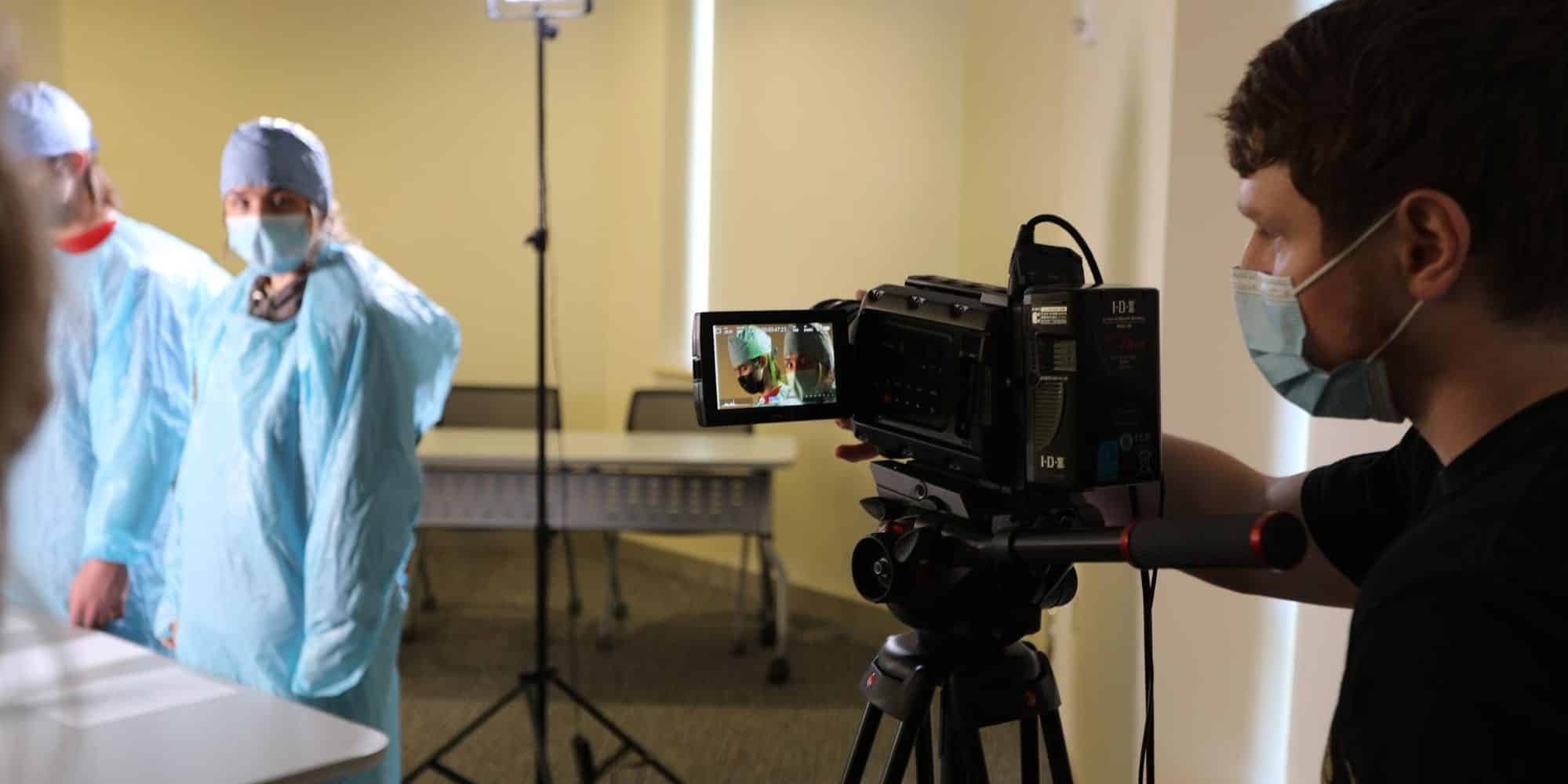 Student videographer films students wearing scrubs