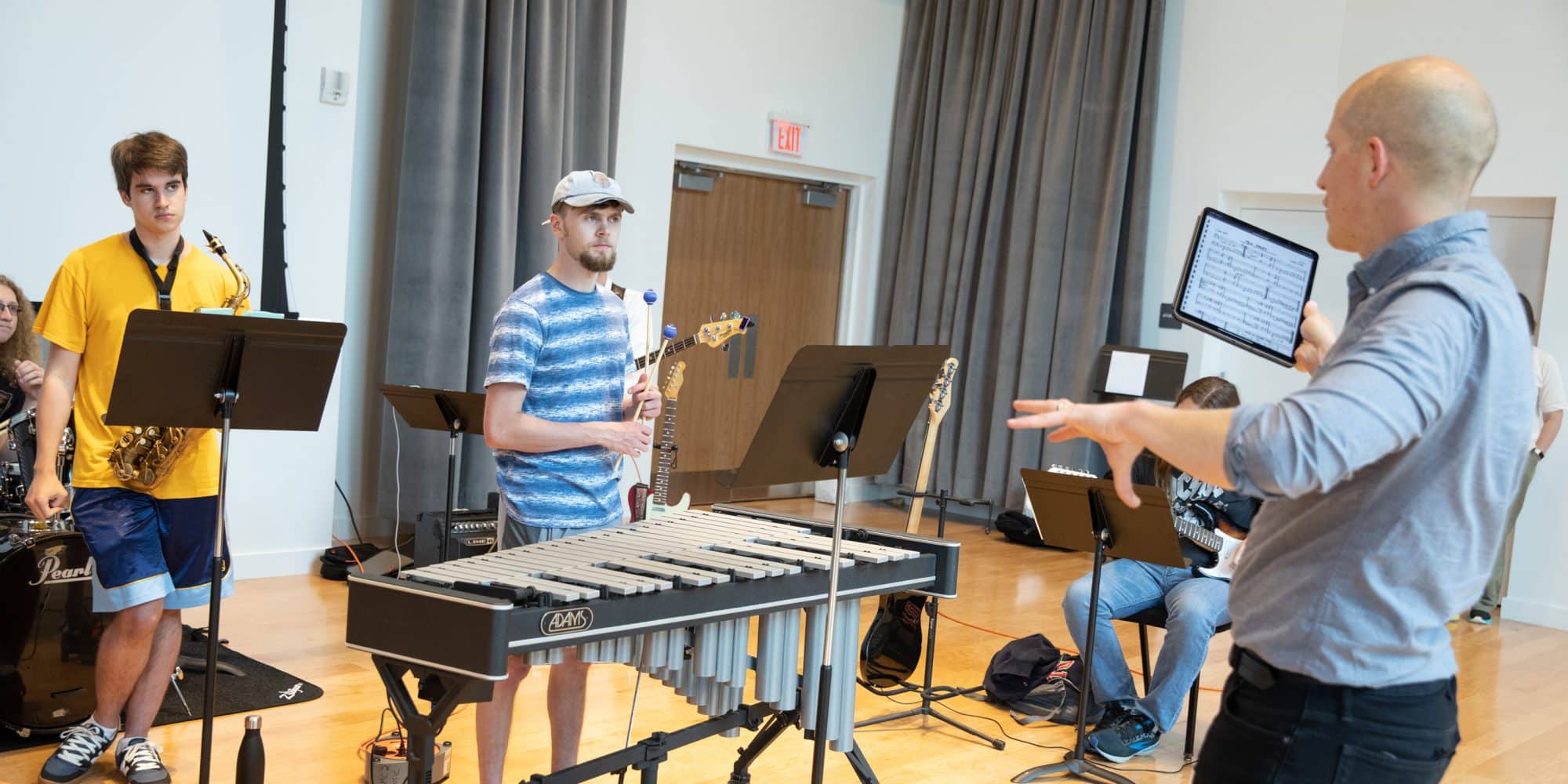 music teacher instructs student musicians during rehearsal