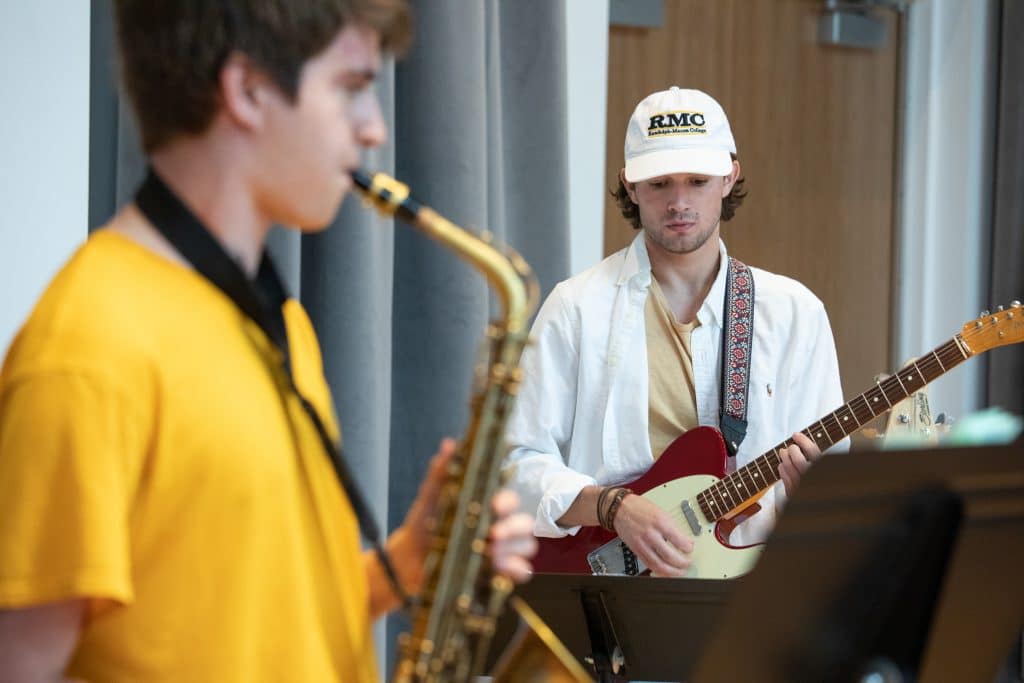 jazz musicians playing sax with guitarist in the background