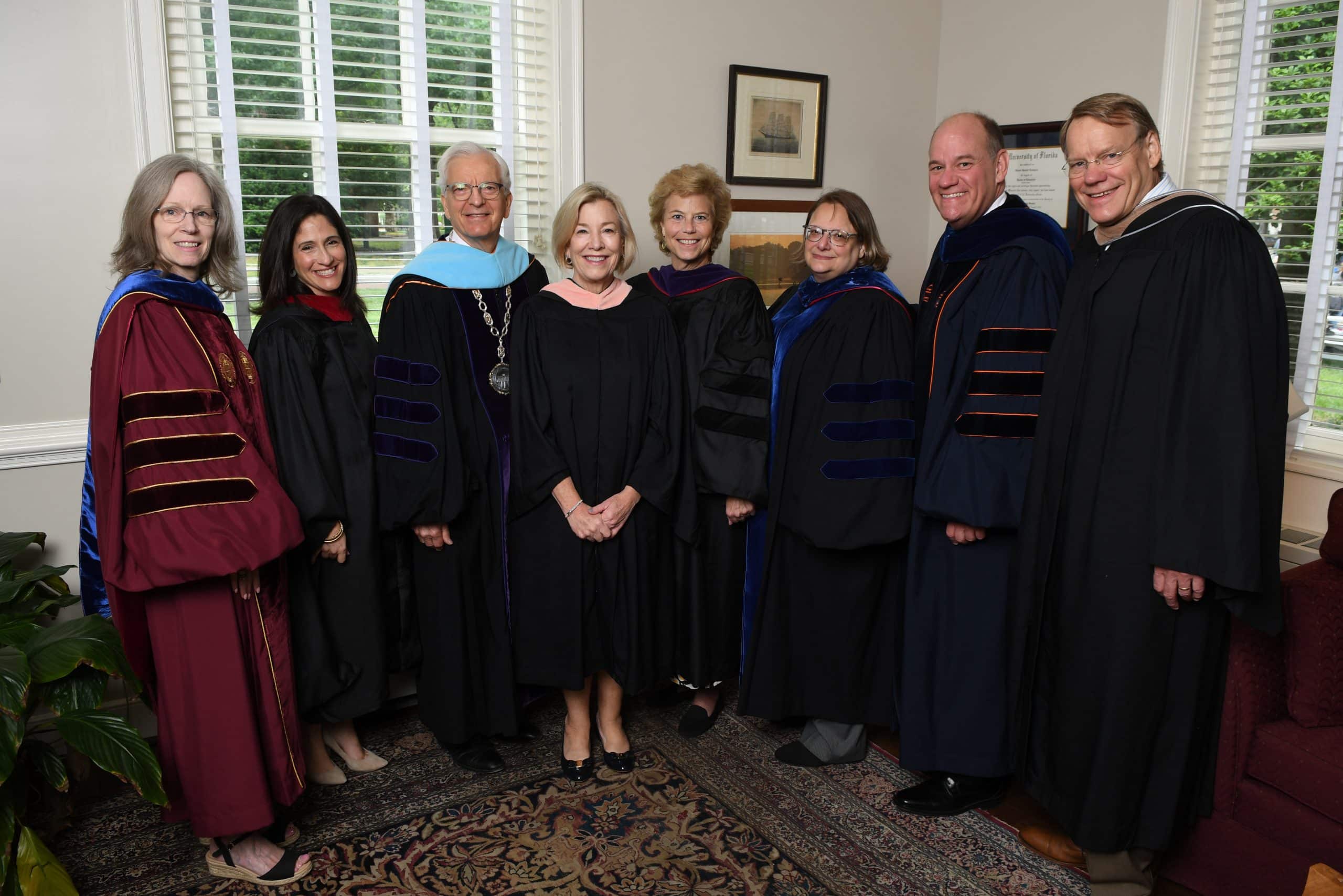 Eight adults in graduation robes