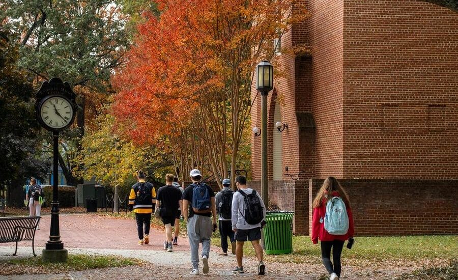 Students walking under fall foliate near old campus