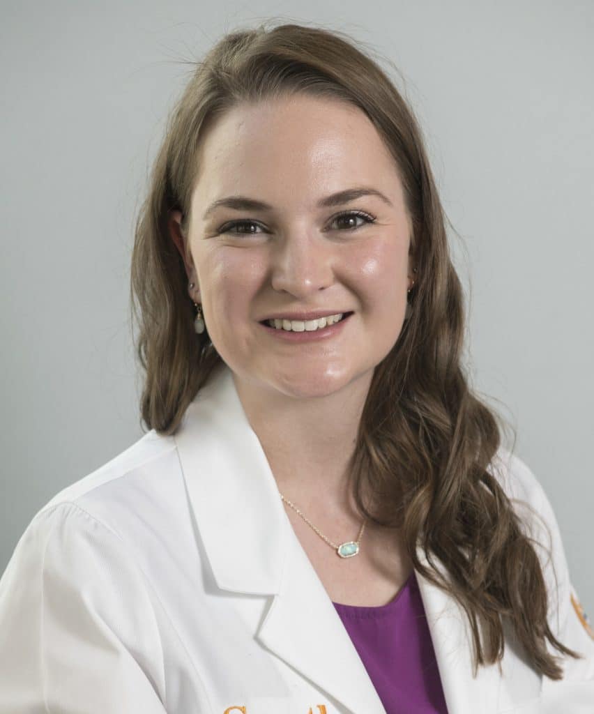A pre-Physician Assistant woman in a white lab coat smiling.