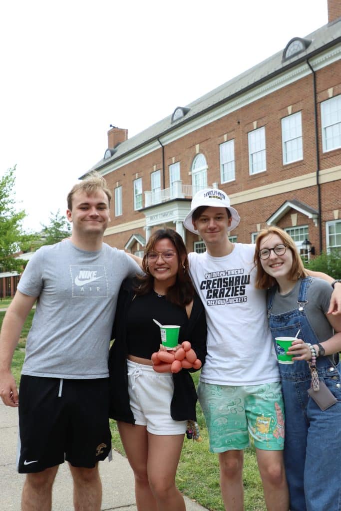 A group of people posing in front of a brick building for the Common Activities Board.