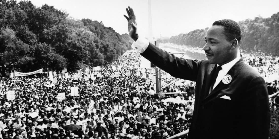 Martin luther king, jr. waving at a large crowed in front of the Lincoln memorial