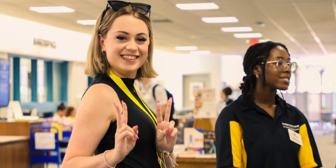 Admitted students posing for a peace sign in a library.