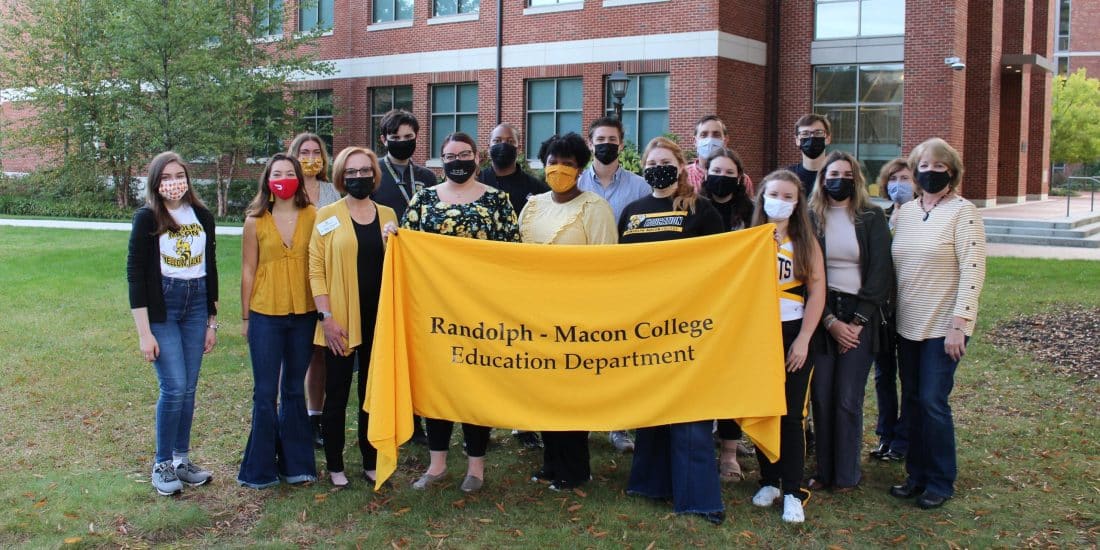Students, Professors, and Alumni holding a yellow Randolph-Macon College Education Department Banner