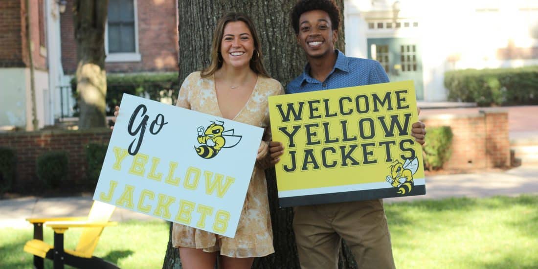 Two people holding signs that say "welcome yellow jackets"