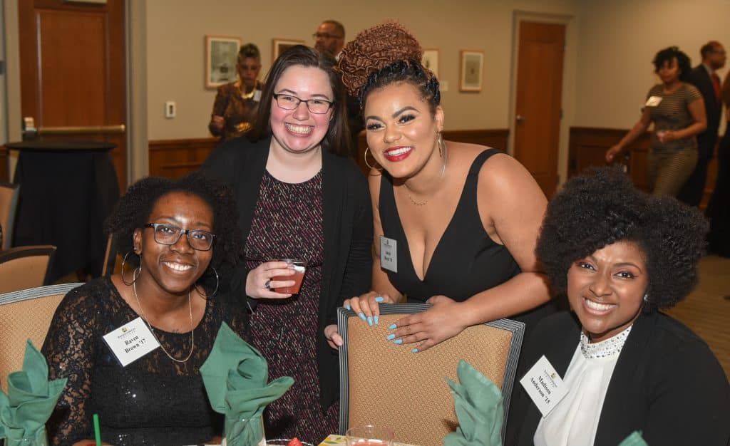Four women posing for a photo at a Multicultural Alumni Association event.