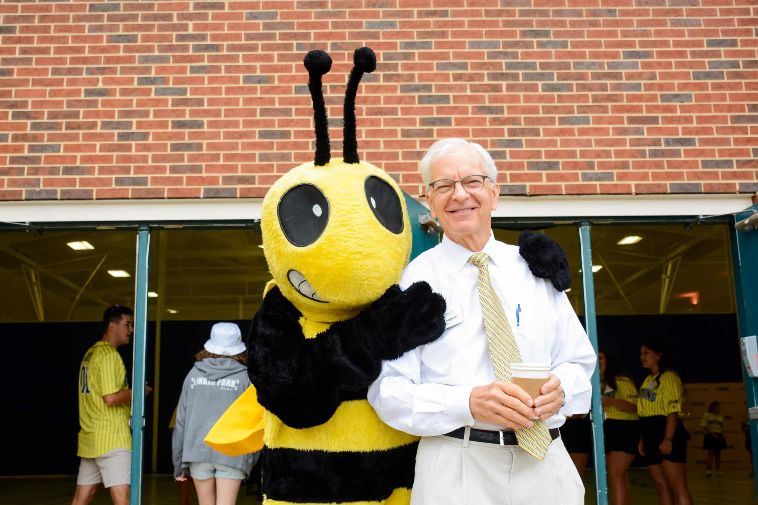 President Lindgren hugs Buzz mascot in front of a building.