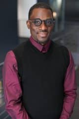 Antonio Hunt, a black man wearing glasses and a vest.