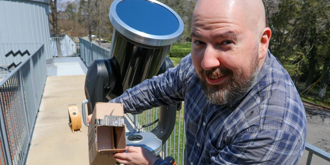 Man demonstrating a solar observation instrument outdoors.